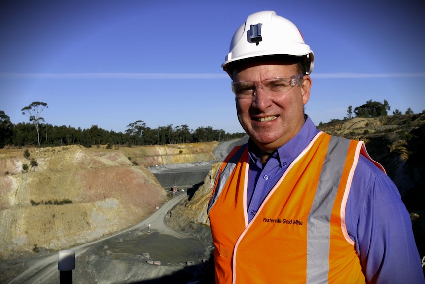 Ian Holland stands on the lip of the open cut Fosterville Mine he wears protective clothing and glasses, it's a sunny day