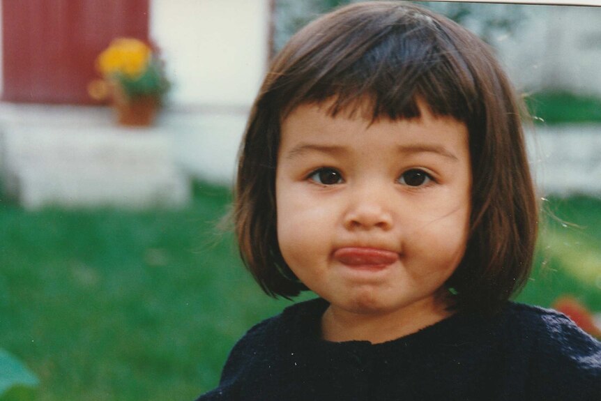 A little girl with a bob haircut stick her tongue out of her mouth