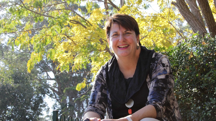 Melissa Green sits on a picnic table smiling into camera.