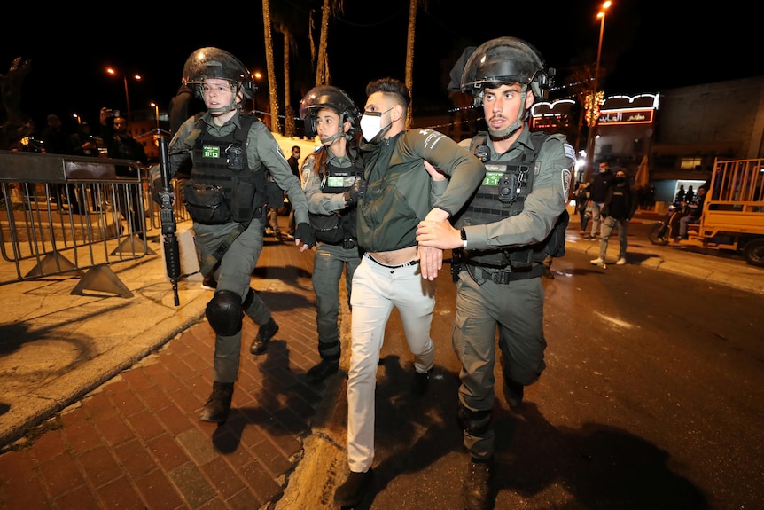 Israeli police officers detain a Palestinian man during clashes.