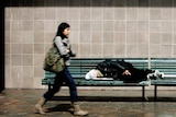 Homeless man sleeping on a bench in Sydney.