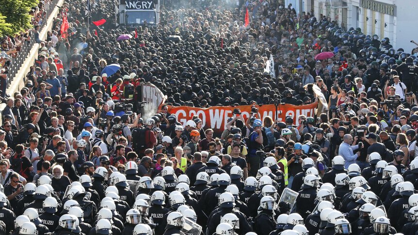 German riot police line up in front of thousands of protesters.