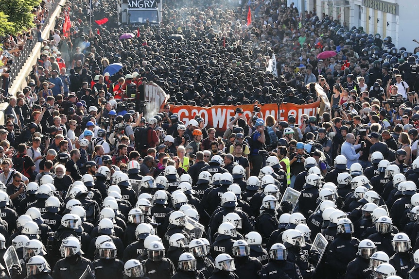 German riot police line up in front of thousands of protesters.