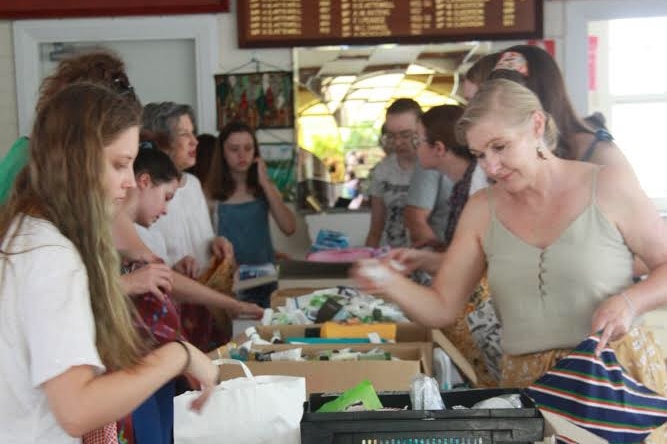 People are seen packing bags filled with menstrual and hygiene products at a Country Women's Association hall.