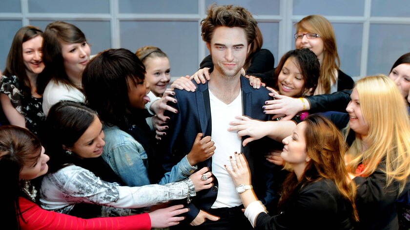 A group of girls pose next to a wax model of Robert Pattinson