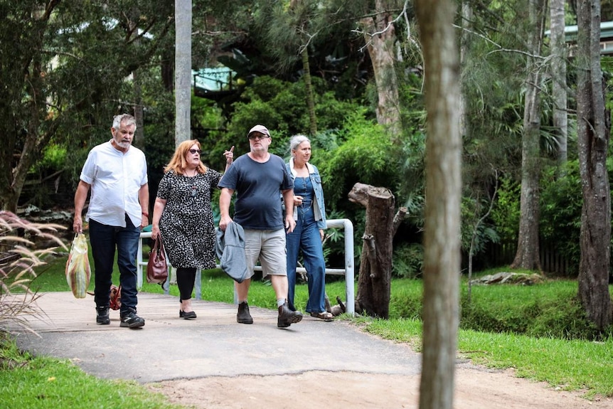 Two men and two women walk over a footbridge at Great Mackerel Beach.