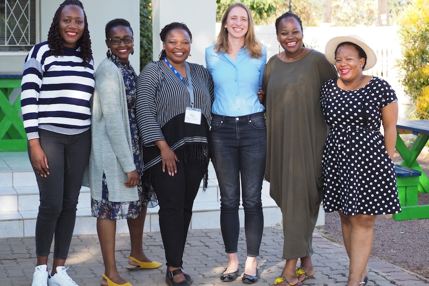 Six women stand outside smiling at the camera.