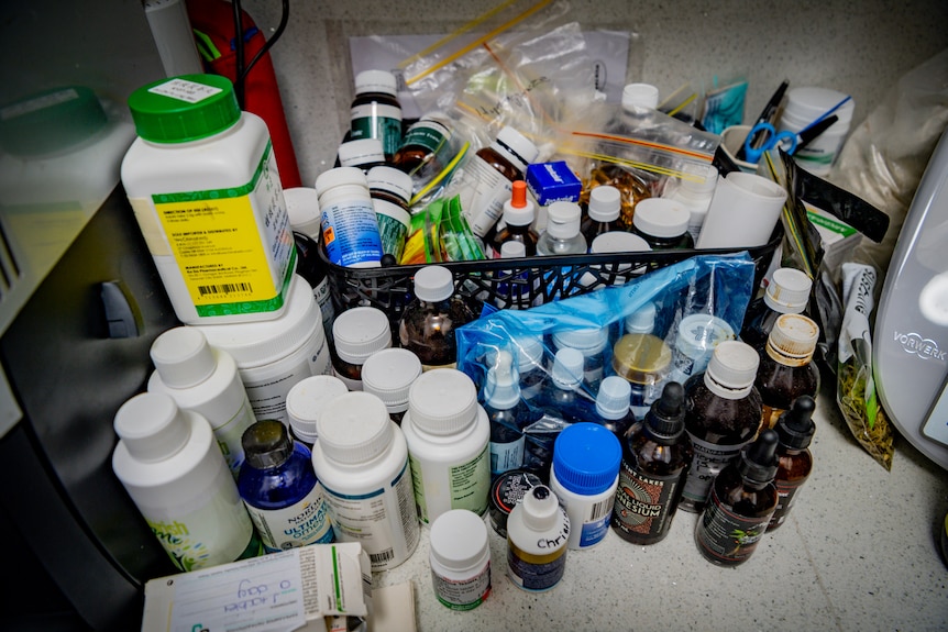 Dozens of bottles and packets of medicine sitting on a bench
