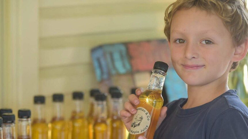 Young child holding onto lemonade bottles.