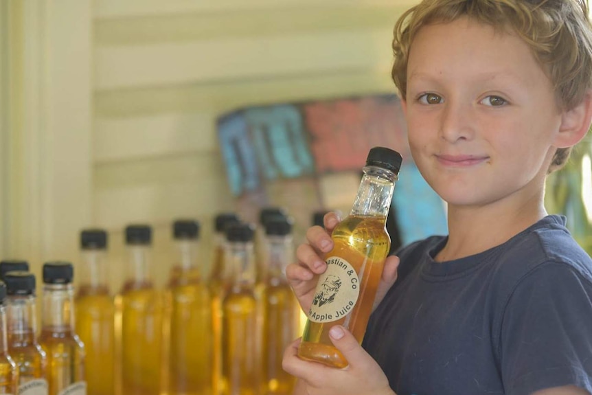 Young child holding onto lemonade bottles.