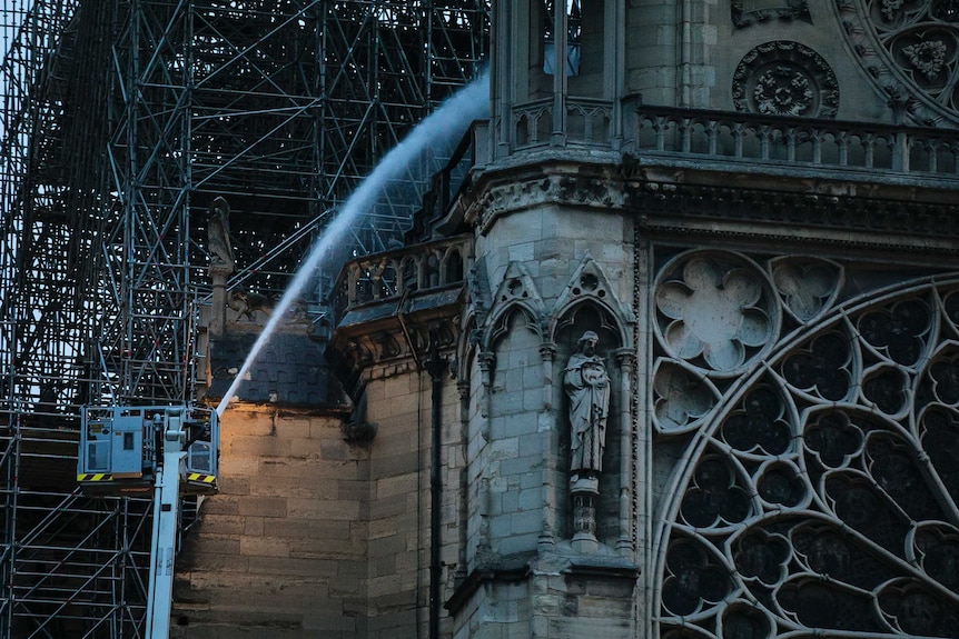 Firefighters spray water on the singed Notre Dame cathedral
