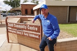 A man stands beside a sign that says South Community Centre in Broken Hill.