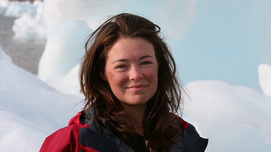 Woman in a red jacket standing in front of snow and ice.
