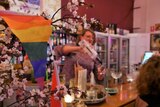 an lgbt+ flag in a bar with a woman pouring drinks behind it