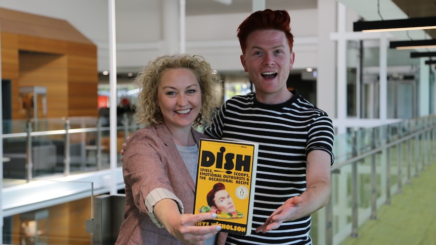 Rhys Nicholson and Zan Rowe pose with a picture of Rhy's new memoir 'Dish'
