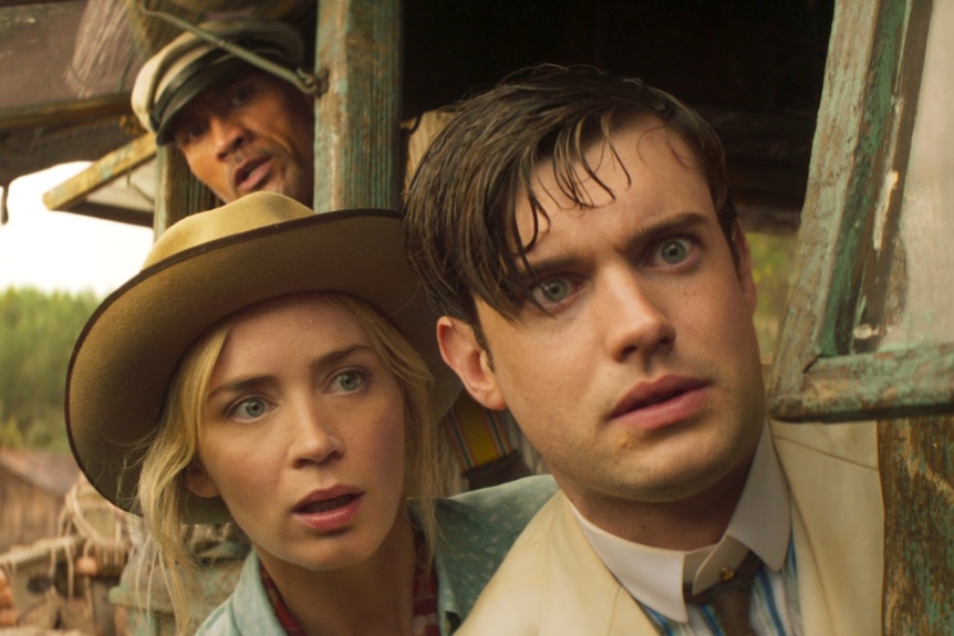 Dwayne Johnson, Emily Blunt and Jack Whitehall lean out over the side of a wooden boat with fearful expressions