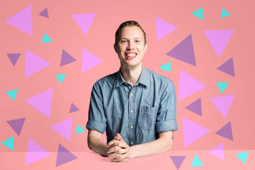 Patrick Lenton smiling and holding hands togetherin front of a pink illustrated background with purple and teal triangles.