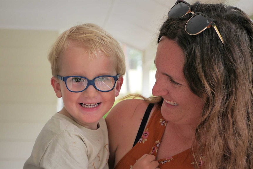 Hunter smiling and wearing glasses in his mum Emma's arms.