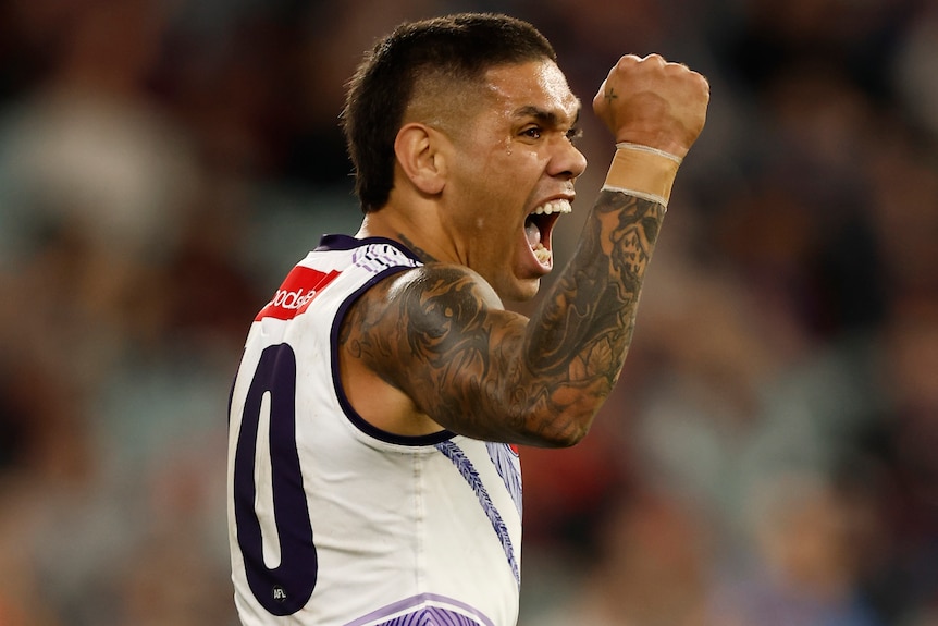 A Fremantle AFL player pumps his right fist as he celebrates a goal against Melbourne.