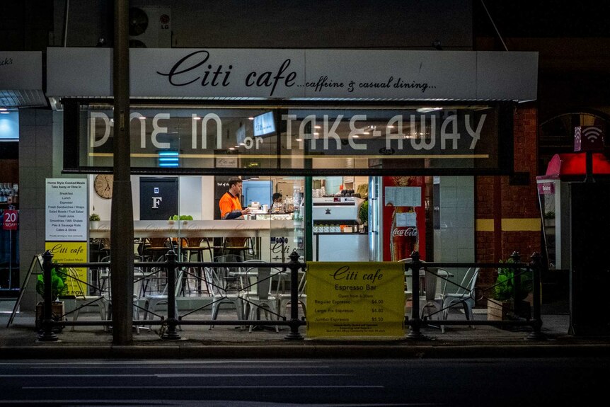 A man stands inside a cafe.