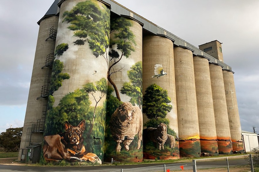 Silos with a painting of a kelpie and sheep on closest silos.