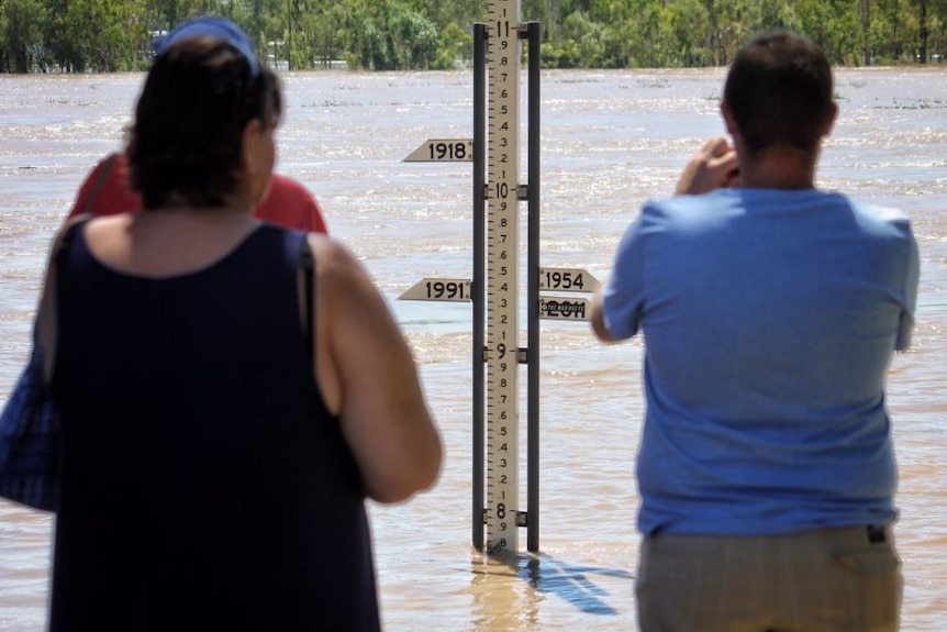 People look at the flood gauge in the Fitzroy River in Rockhampton