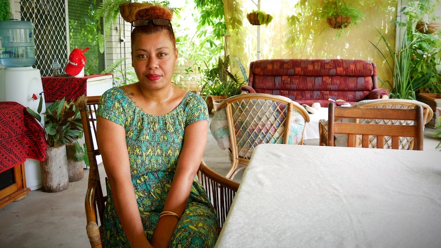 A woman sitting on a chair on her patio, looking at the camera. 