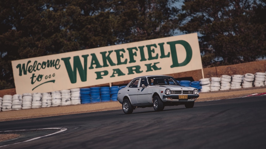 A car driving on a racetrack in front of a sign that says "Wakefield Park".