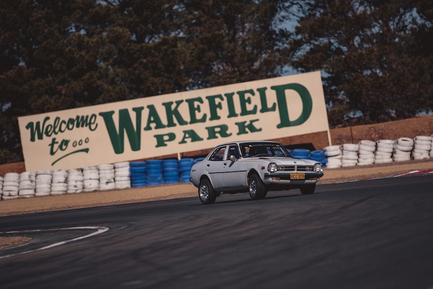 A car driving on a racetrack in front of a sign that says "Wakefield Park".