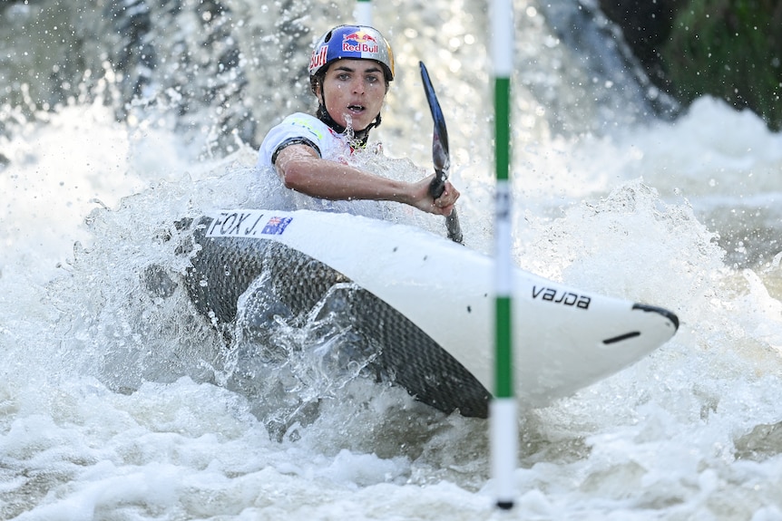 Jess Fox stares down the course as she steers her kayak through whitewater toward gates during a run.