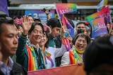 Lai Ching-te smile s and waves in a crowd of people waving rainbow flags