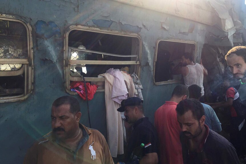 Men look through windows of the wreckage of a train crash