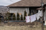 Washing hangs on a line outside a house with a tiled roof