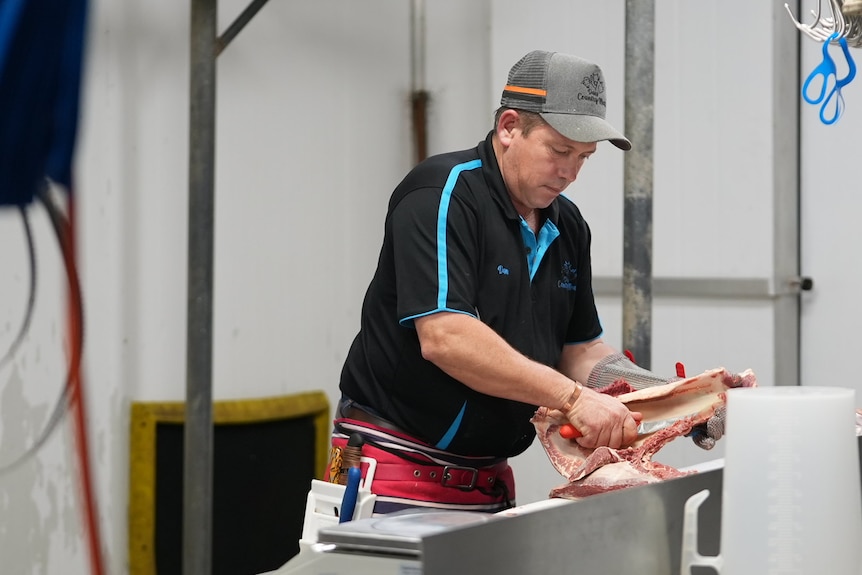 Butcher Dan Walton cuts up meat in his processing shed