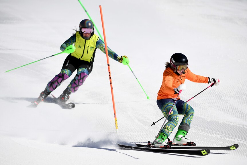 Melissa Perrine porte un gilet jaune haute visibilité et skie derrière son guide, Bobbi Kelly, portant une veste orange plusieurs mètres devant
