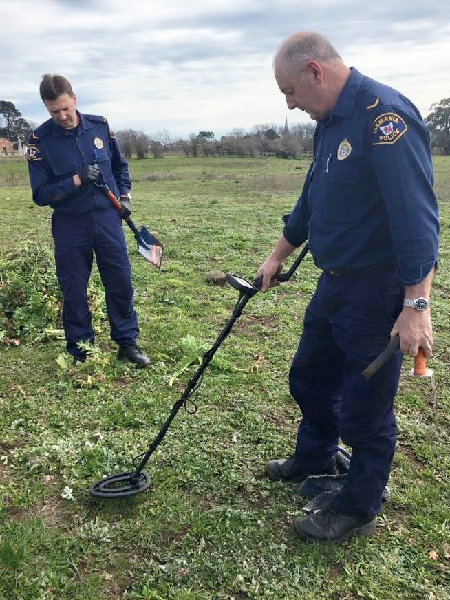 Two police officers searching a paddock yard in Tasmania.