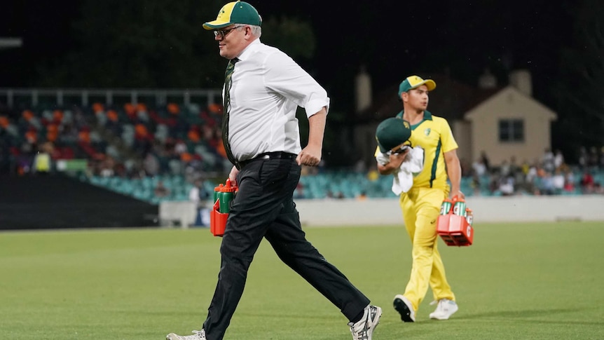 Scott Morrison runs off the field with drinks during the Prime Minister's XI cricket match.