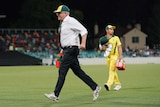 Scott Morrison runs off the field with drinks during the Prime Minister's XI cricket match.