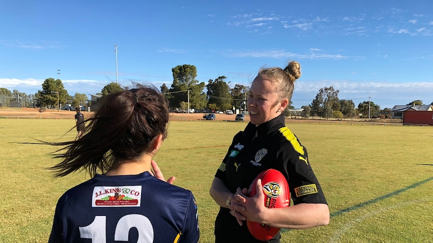 Female footballer chats to younger female about women's football