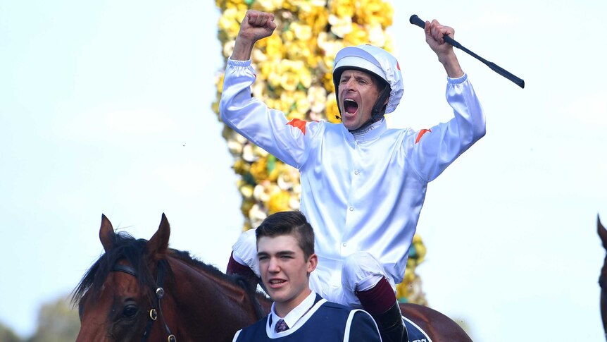 A jockey pumps both his fists as sits on top of a horse after riding it to victory in the Golden Slipper.