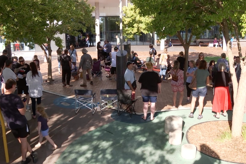 People standing around among trees outside a building