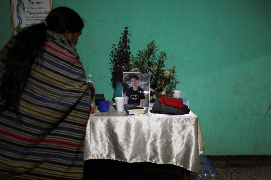 A woman stands next to an altar for 14-year-old Wilmer.