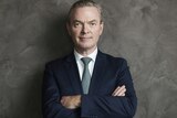Christopher Pyne smiles with his arms crossed, wearing a suit and tie.