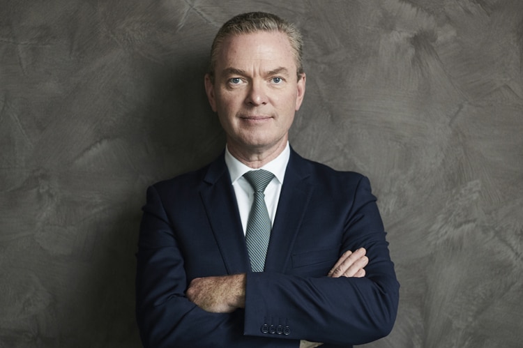 Christopher Pyne smiles with his arms crossed, wearing a suit and tie.
