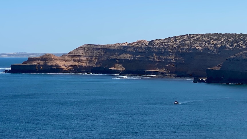 A boat on the water near cliffs.
