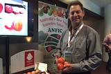 A man standing in a conference room holding a box of apples
