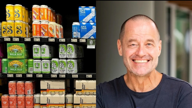 shelves of colourful beer cans and bust of smiling man with short cropped hair and a blue t-shirt