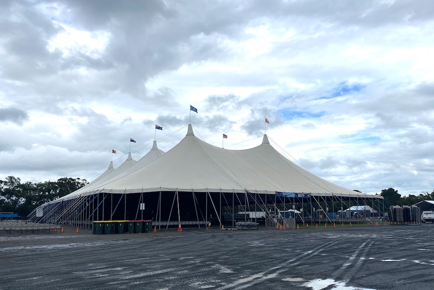 A huge tent in a field, ready for a music festival.