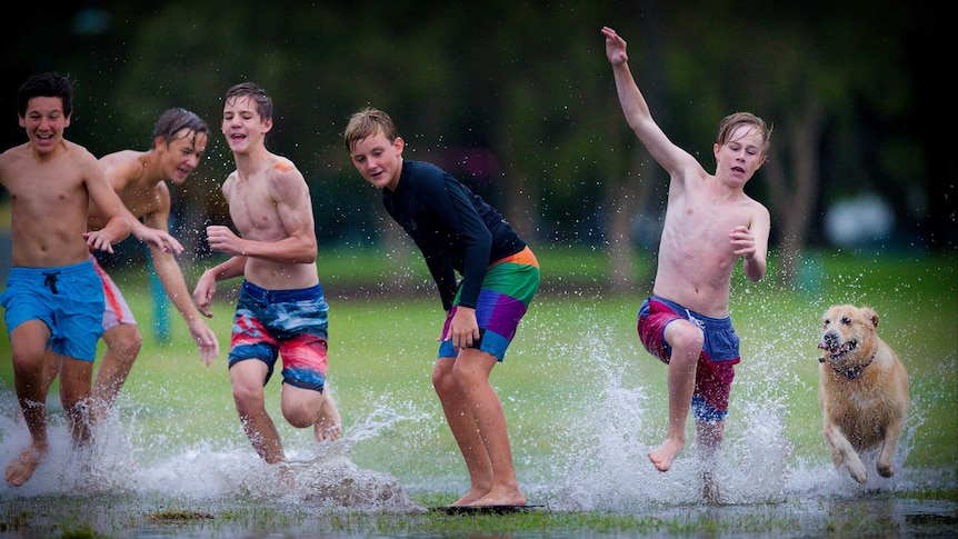Boys surf using "boogie boards" in a park on the Wynnum foreshore from rain after Tropical Cyclone Marcia made land in Brisbane on February 20, 2015