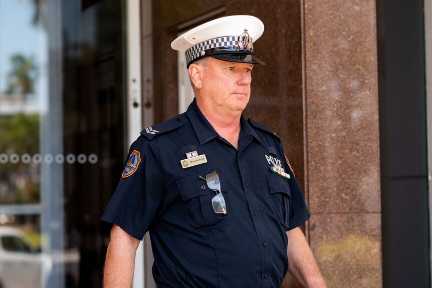A middle-aged white police officer in uniform leaving court.